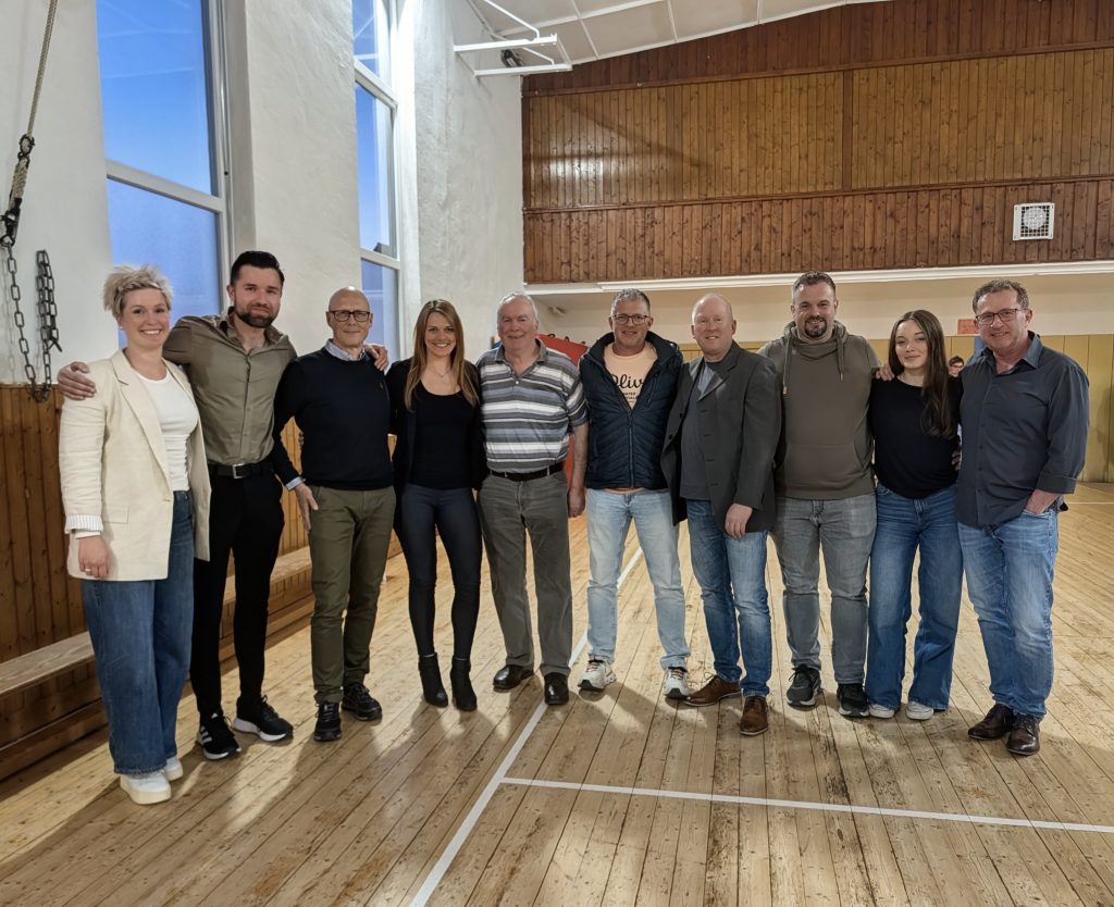 Elf Mitglieder des Vorstands des Stadtsportverbands Bad Laasphe stehen nebeneinander in einer Turnhalle mit Holzboden und Sprossenwand.